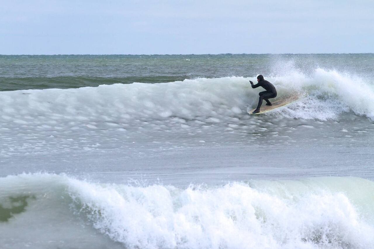 A man in a wetsuit surfs a wave in the winter.