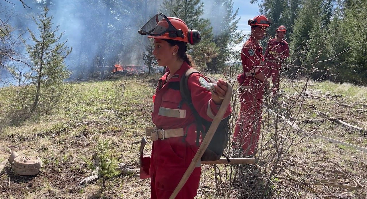 default-413 A woman in firefighting gear is seen with others amid smoky conditions.